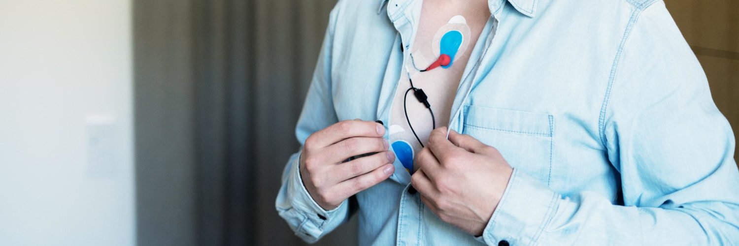 Miehellä on paita hieman auki ja rintakehään on kiinnitetty EKG pitkäaikaisseuranta mittauslaitteet.