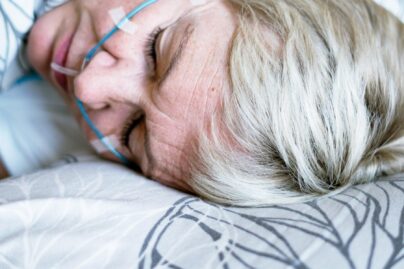 Vaaleahiuksinen nainen nukkuu verenpaineen mittauslaitteet päällä.