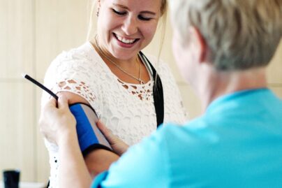 Vaaleahiuksisen naisen verenpainetta mitataan.