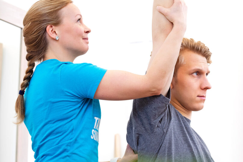 Naisterapeutti tekee kädenojennusliikettä miesasiakkaalle.