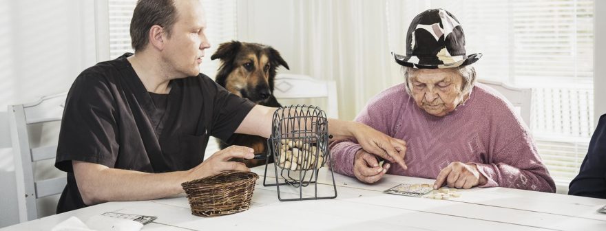 Mummu ja hoitaja pelaavat bingoa yhdessä.