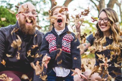 perhe leikkii puun lehdillä