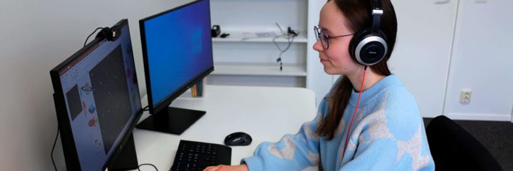 nainen kuulokkeet päässä tietokoneella