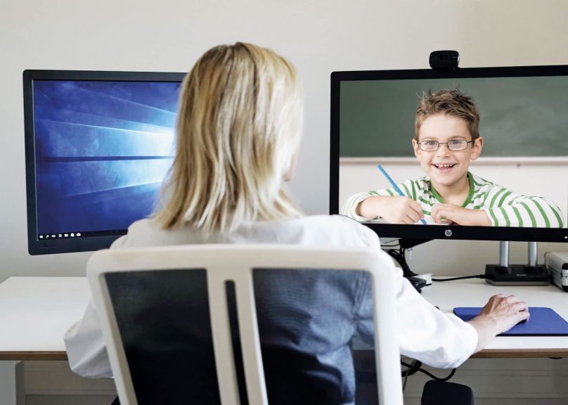 naisterapeutti keskustelee tietokoneen kautta lapsiasiakkaalle joka hymyilee tietokoneen ruudussa