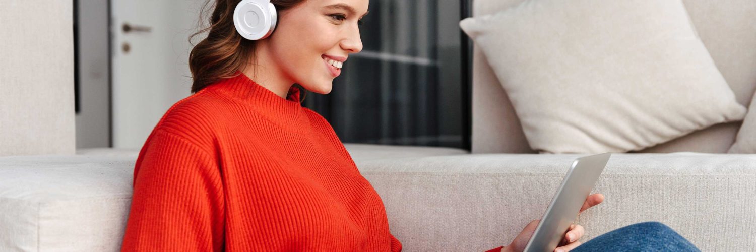 nainen istuu kuulokkeet paassa kannettava tietokone sylissa