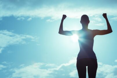 nainen tuulettaa itsevarmasti urheiluvaatteista vastavalossa