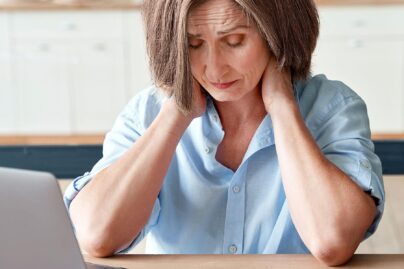 nainen tietokoneella kadet pitelemassa niskaa