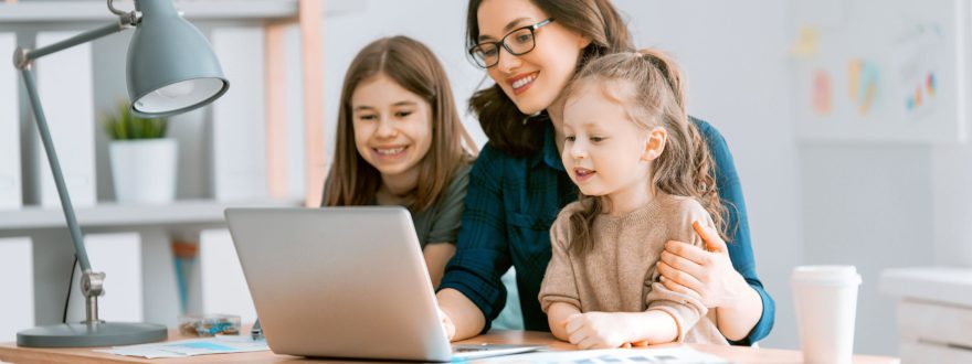 nainen ja kaksi lasta tietokoneella hymyilemassa