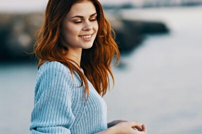 nuori nainen ulkona hymyilee veden aarella
