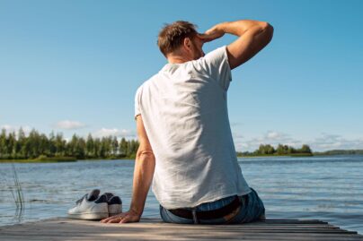 mies istuu laiturilla ja katsoo horisonttiin