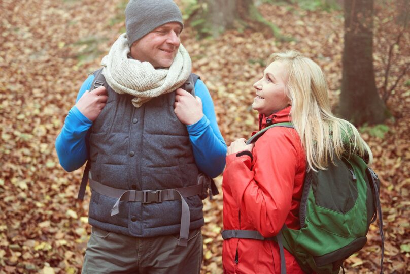 mies ja nainen ulkoilemassa hymyilevat ja katsovat toisiaan