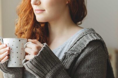 Tyttö juo teetä ja katsoo ikkunasta.