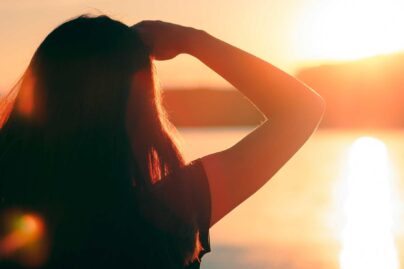 Nainen katsoo auringonlaskua merellä.