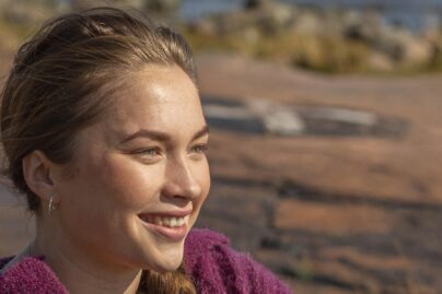 Nuori hymyilee ja istuu kalliolla