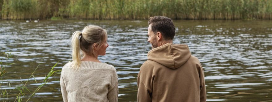 Nainen ja mies istuvat laiturilla ja katsovat toisiaan