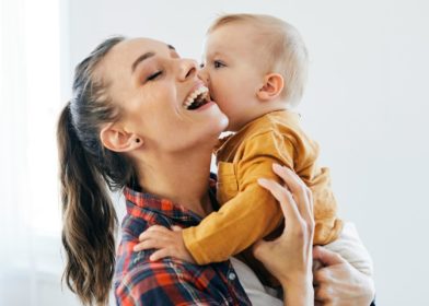 nainen nauraa ja sylissä vauva
