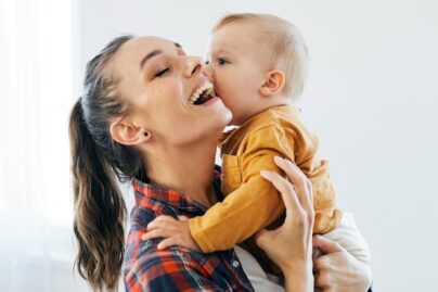 nainen nauraa ja sylissä vauva