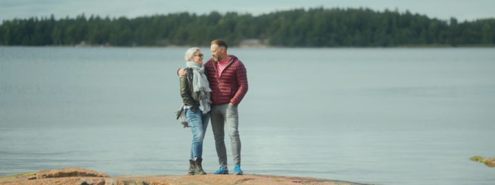 mies ja nainen seisovat ulkona rantakalliolla