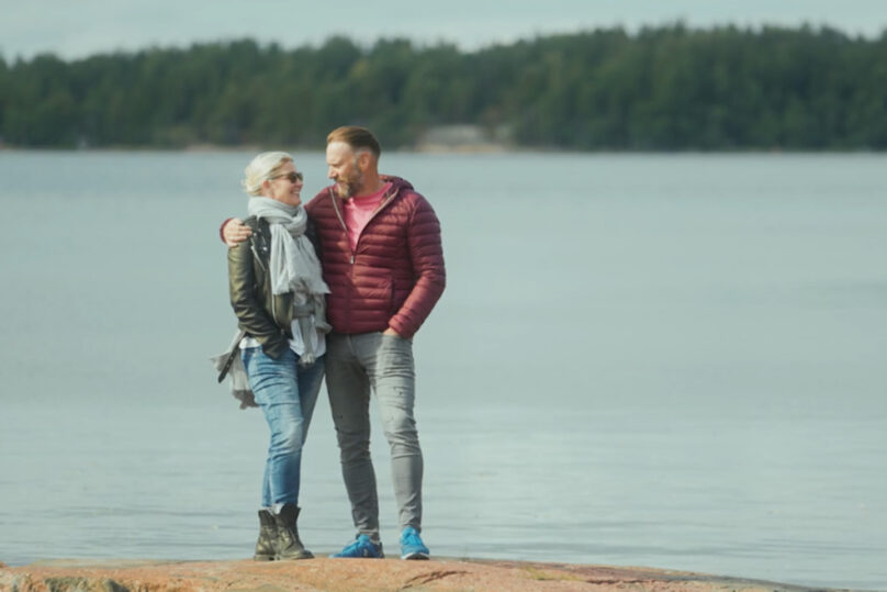 mies ja nainen seisovat ulkona rantakalliolla