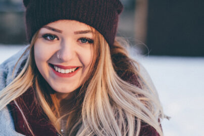 Nainen seisoo talvisessa maisemassa ja hymyilee