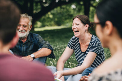 Nainen iloisena puistossa ystäviensä kanssa