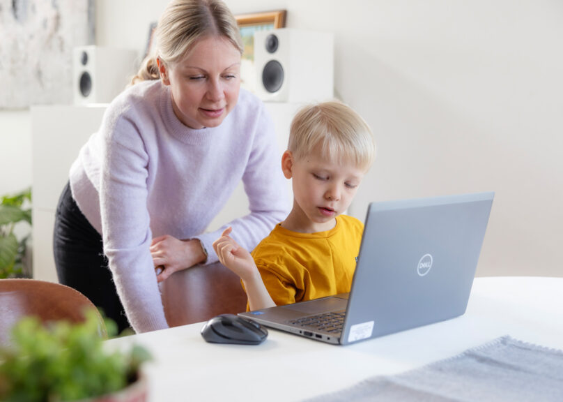 Coronaria kuntoutuspalvelujen lapsiasiakas on kotona äitinsä kanssa kannettavan tietokoneen äärellä.