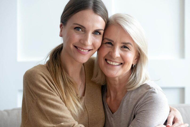 Aikuinen nainen ja tämän iäkkäämpi äiti halaavat.