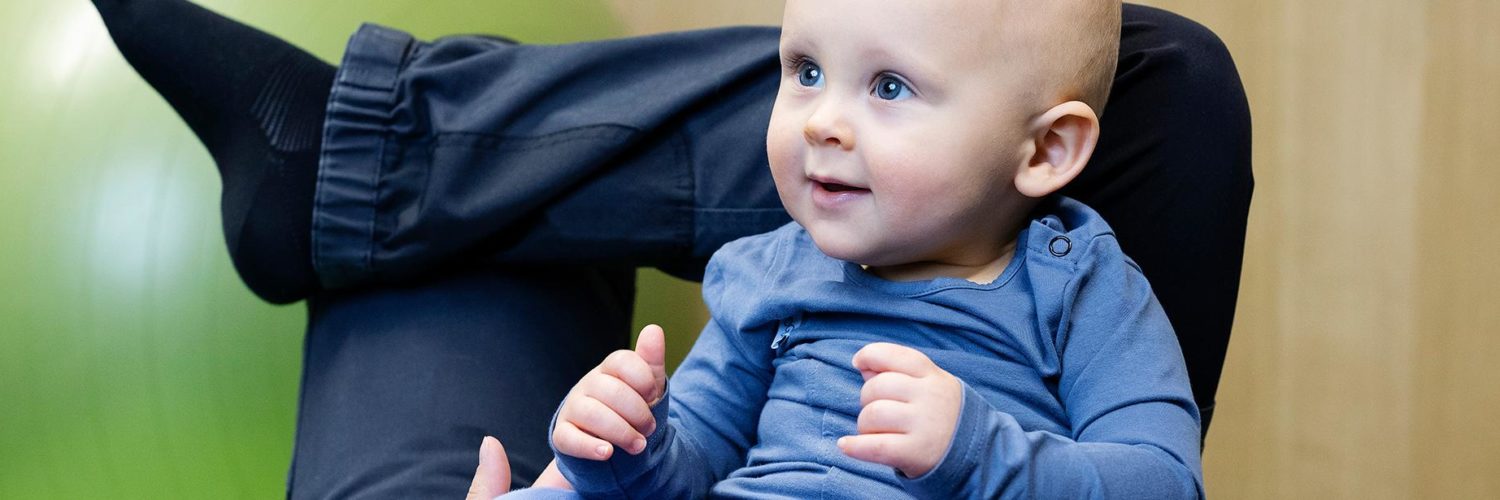 Vauva hymyilee äidin sylissä äitiysfysioterapiassa.