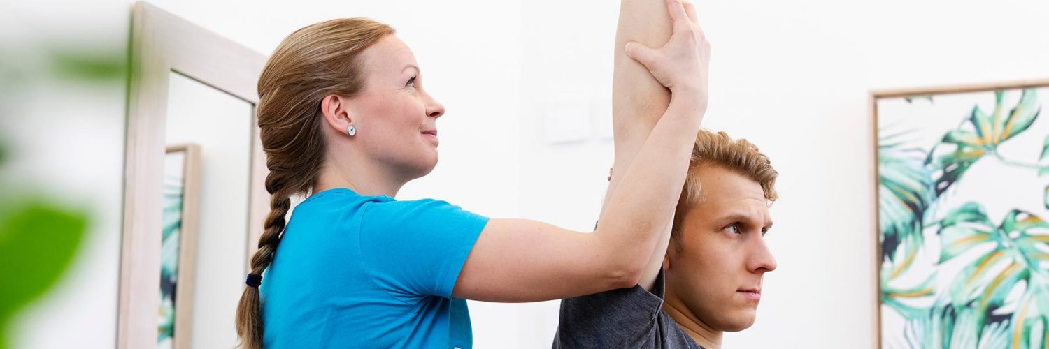 Fysioterapeutti tekee asiakkaalle fysioterapian vastaanotolla passiivisia venytyksiä.