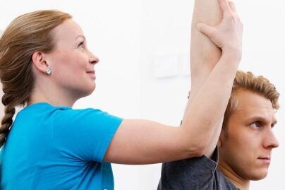 Fysioterapeutti tekee asiakkaalle fysioterapian vastaanotolla passiivisia venytyksiä.