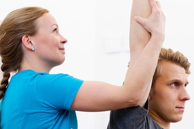 Fysioterapeutti tekee asiakkaalle fysioterapian vastaanotolla passiivisia venytyksiä.