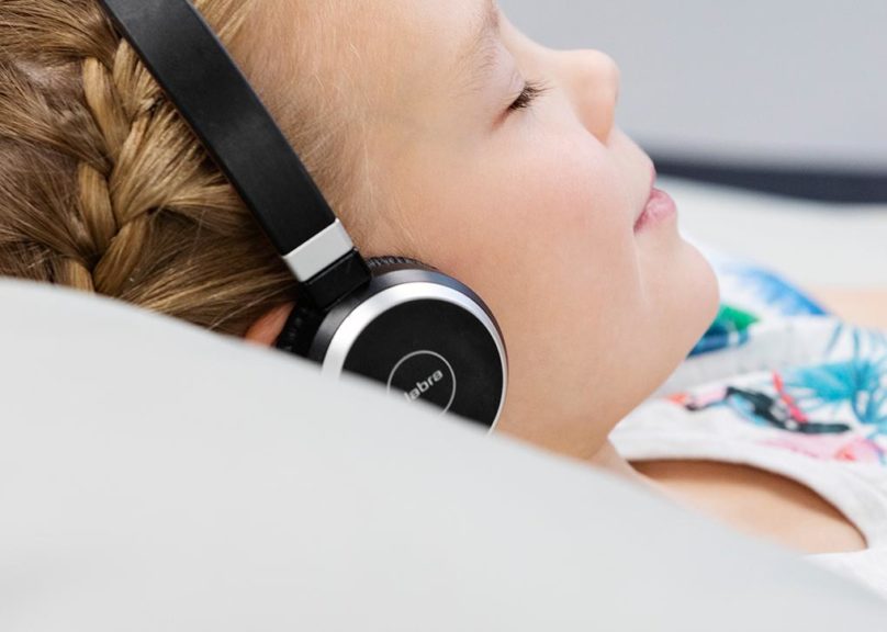 Lapsiasiakas makoilee säkkituolissa lasten fysioterapiassa ja tekee kuulokkeet päässä rentoutumisharjoitusta.