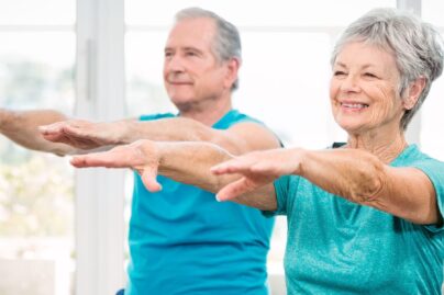 seniorinainen ja seniorimies tekevat tasapainoharjoituksia kadet suoristettuna eteenpain