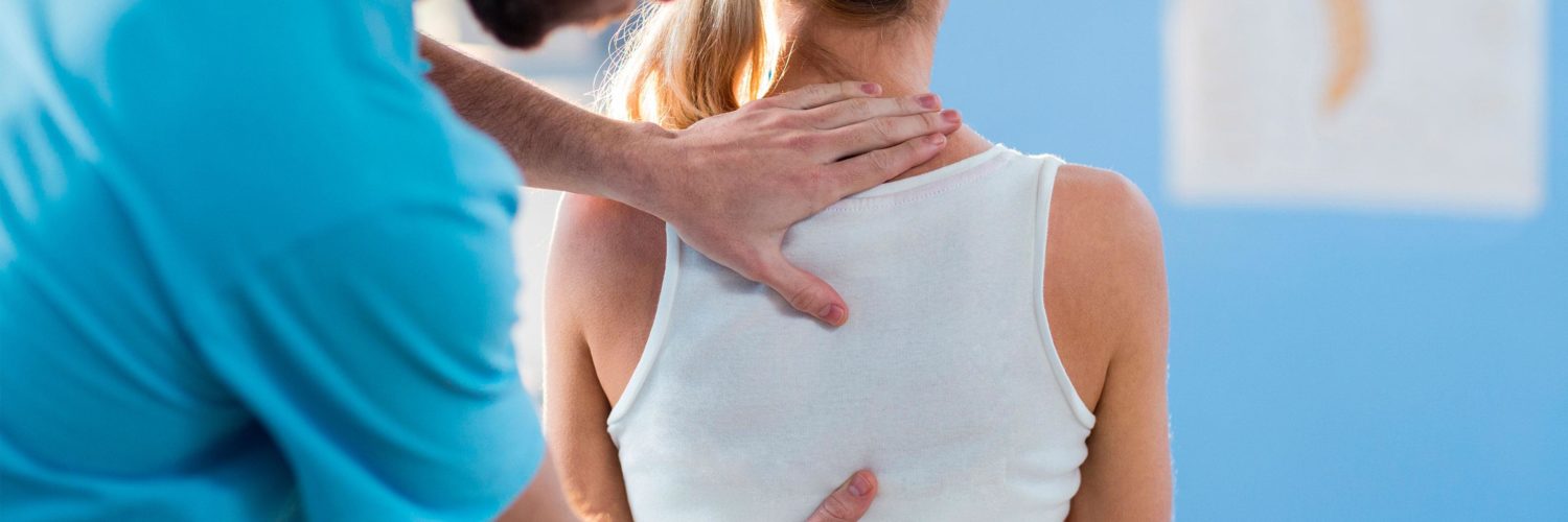 fysioterapeuttimies tutkii naisaisakkaan selkaa painelemalla kasilla selasta