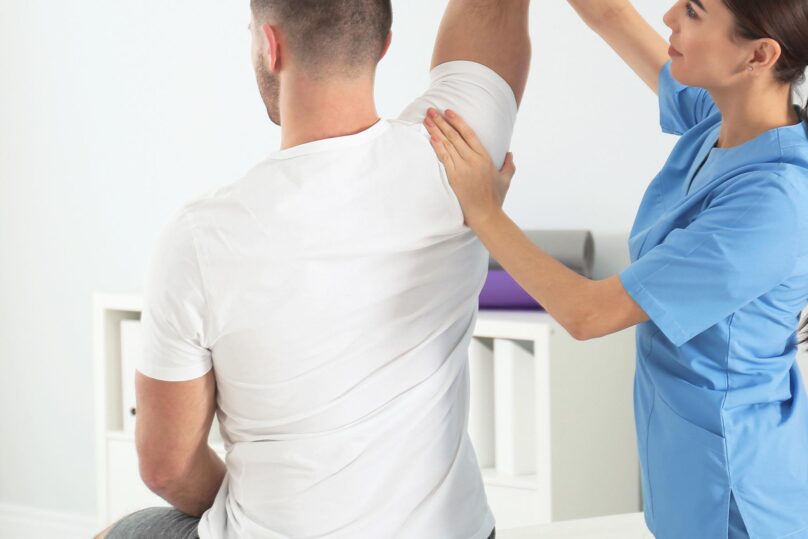 naisfysioterapeutti tutkii miesasiakkaan selkaa