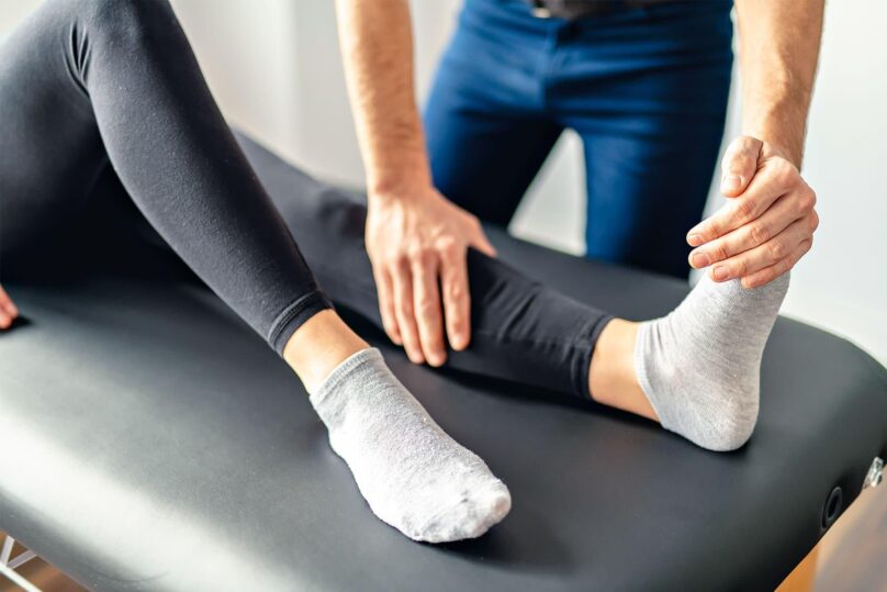 fysioterapeutti tutkii pohjetta ja jalkaa
