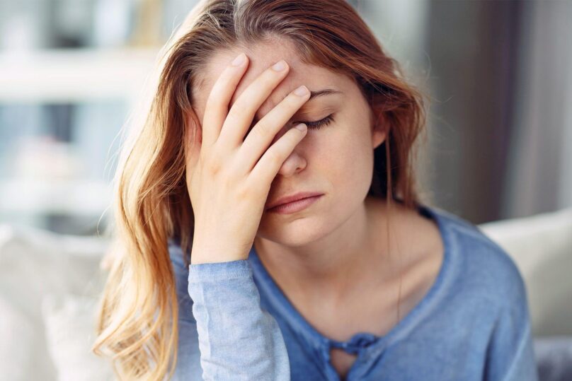 nainen pitaa kadella kiinni otsasta silmat kiinni