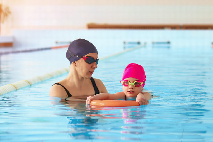 Nainen ja lapsi uima-altaassa tekemässä harjoitusta