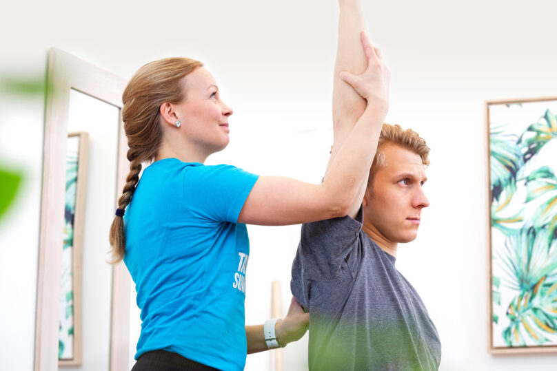 Naisterapeutti tekee kädenojennusliikettä miesasiakkaalle.