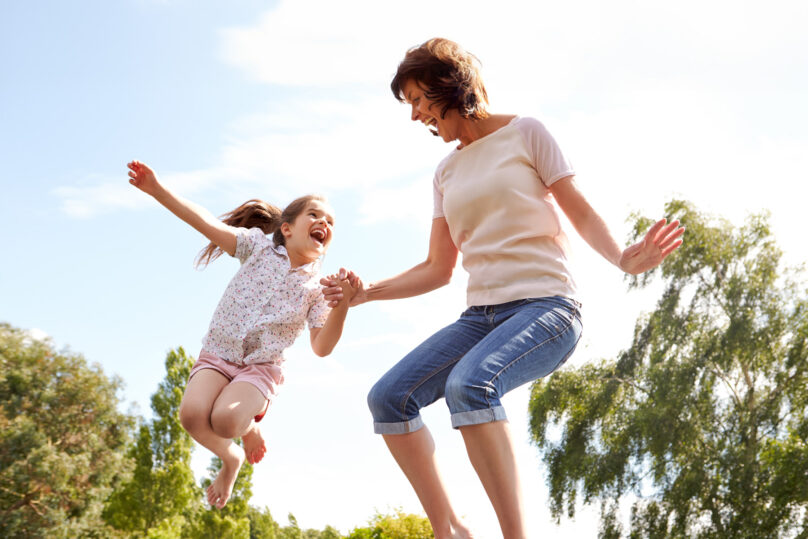 Äiti ja tytär hyppimässä trampoliinilla kesällä