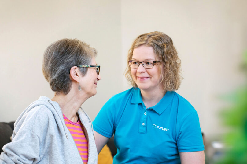 Naisterapeutti ja iäkäs naisasiakas hymyilevät toisilleen