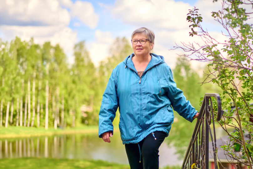 Iäskäs nainen nousee portaita mökkirannassa.