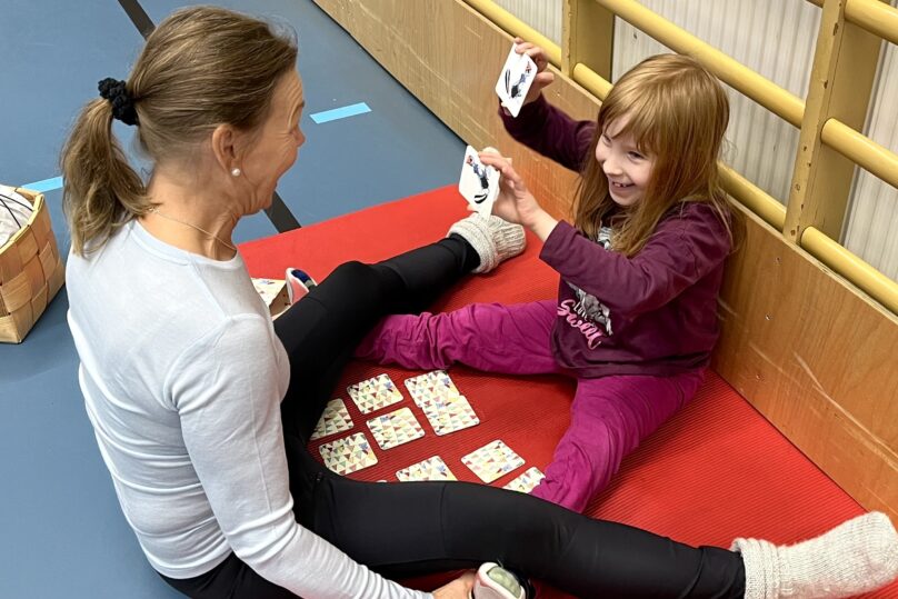 Fysioterapeutti ja lapsi istuvat jumppamatolla ja tekevät harjoitusta