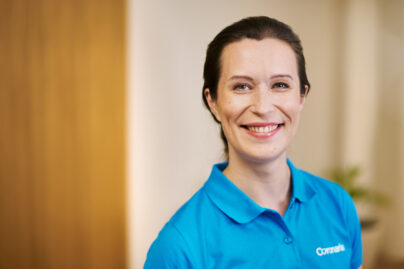 Tummahiuksinen nainen Coronarian pikeepaidassa sisällä