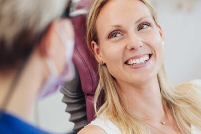 Nainen hymyilee ja katsoo hammaslääkäriä.