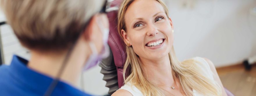 Nainen hymyilee ja katsoo hammaslääkäriä.