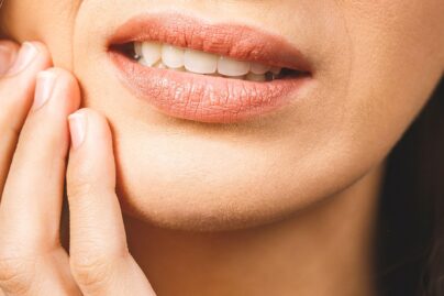 Nainen pitelee kiinni kipeästä hampaasta.