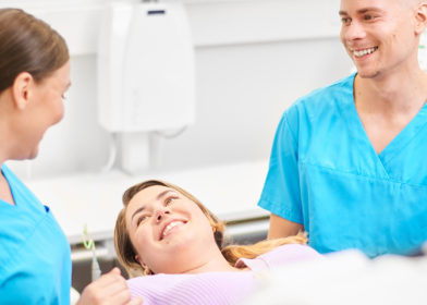 Hammaslääkäri hammashoitaja ja hymyilevä asiakas