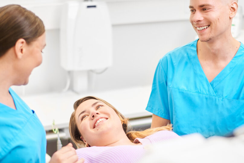 Hammaslääkäri hammashoitaja ja hymyilevä asiakas