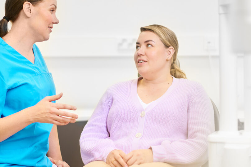 Hammaslääkäri ja asiakas keskustelevat hoitohuoneessa